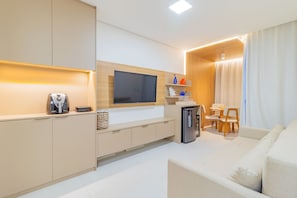 A modern living room with a flat-screen TV, a coffee machine, and a small refrigerator. - Cais Eco #311 - Cobertura Com Piscina by Carpediem (Ipojuca)