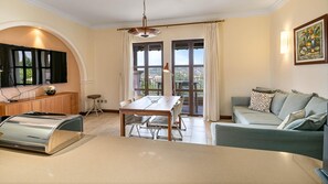 Uma sala de estar moderna com área de jantar, cozinha equipada com forno embutido e uma janela grande com cortinas.