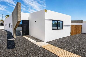 A modern building with a flat roof, a concrete structure on the left, and a wooden fence on the right. - Casa Drago Uno - Three Bedroom Villa, Sleeps 5 (Caleta de Fustes)