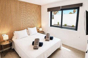 A hotel room with a large bed, two bedside tables with lamps, a window with a view of the outside, and a flat-screen TV mounted on the wall. - Casa Drago Uno - Three Bedroom Villa, Sleeps 5 (Caleta de Fustes)