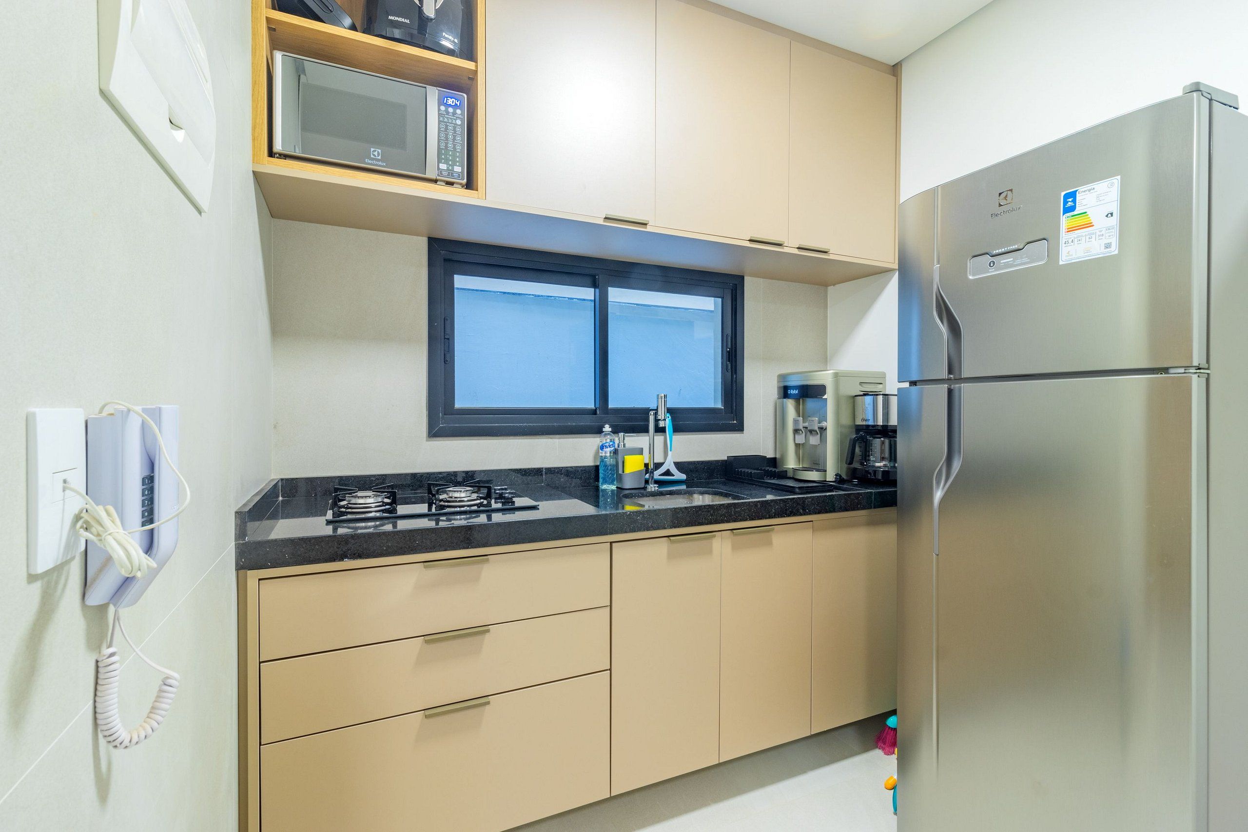 Cozinha compacta com geladeira, micro-ondas, fogão e pia.