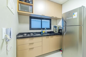 Cozinha compacta com geladeira, micro-ondas, fogão e pia.