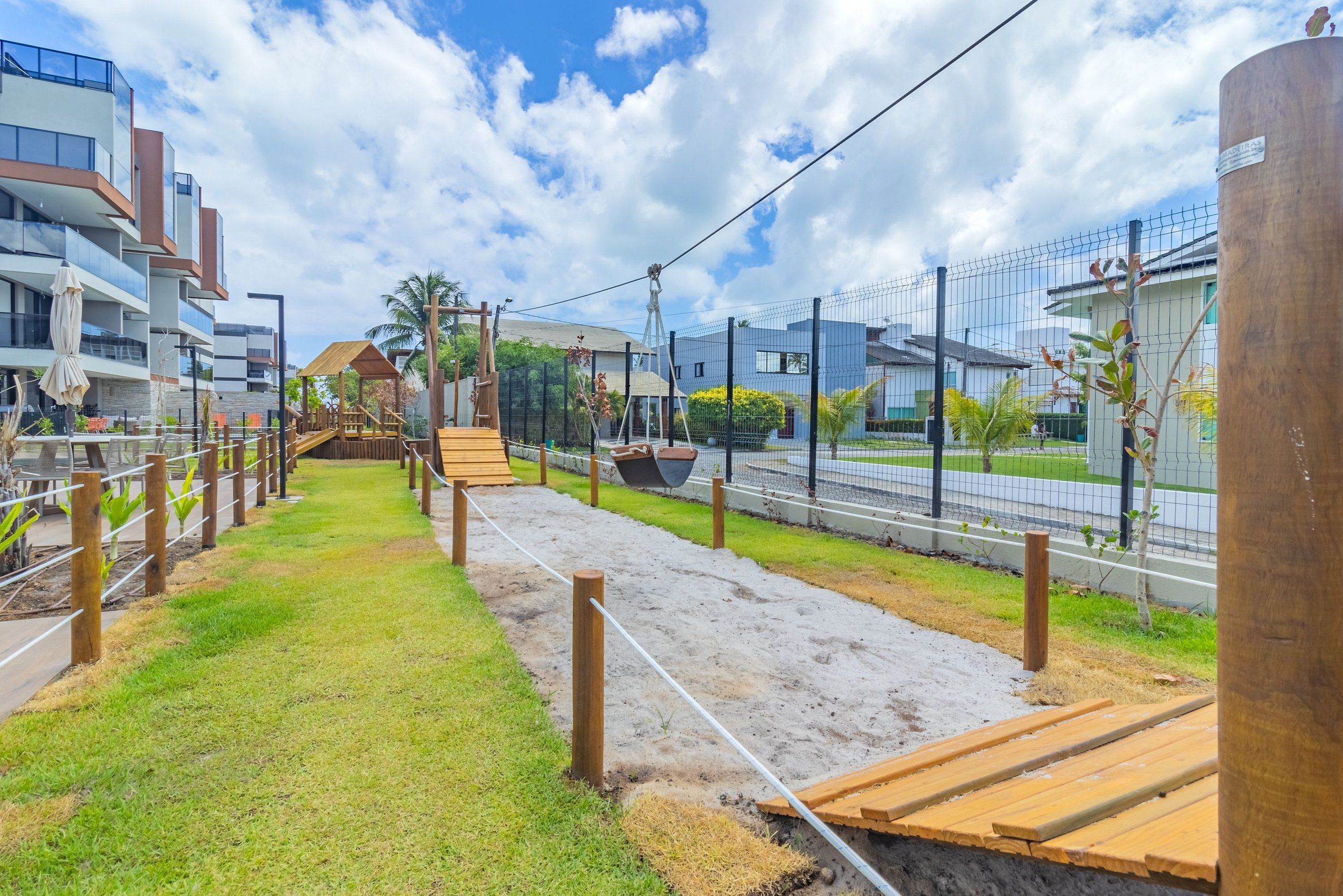 Uma trilha com tábuas de madeira e barreiras de corda, que leva a um gazebo e uma pequena escadaria.