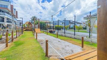 Uma trilha com tábuas de madeira e barreiras de corda, que leva a um gazebo e uma pequena escadaria.