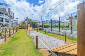 Uma trilha com tábuas de madeira e barreiras de corda, que leva a um gazebo e uma pequena escadaria.
