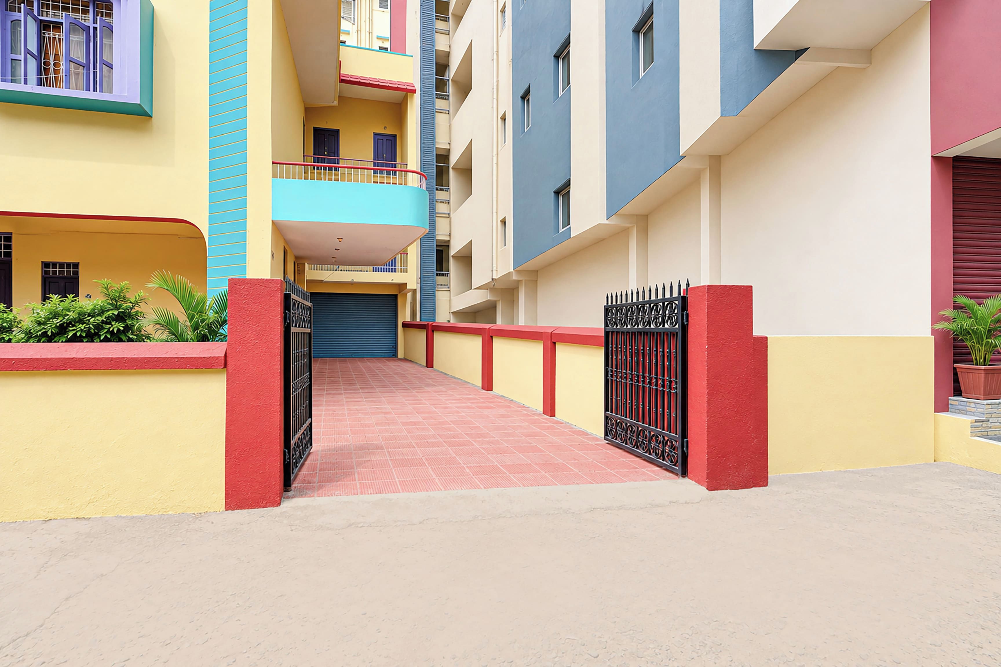 A multi-story residential building with a red-tiled walkway leading to a gated entrance.