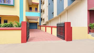 A multi-story residential building with a red-tiled walkway leading to a gated entrance.