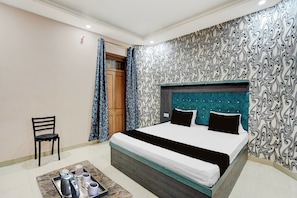 A hotel room with a bed, a chair, and a tray with a kettle and cups. - Collection O Patna Airport Road (Danapur)