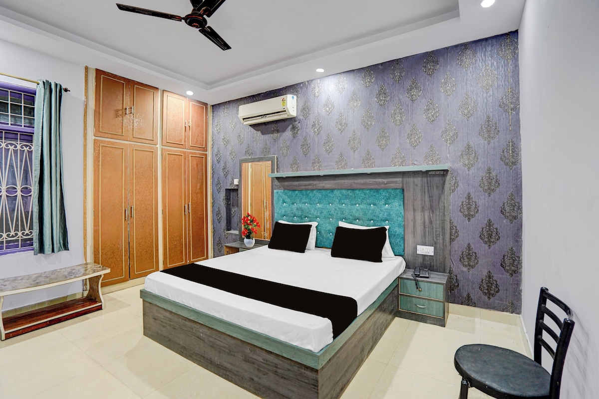 A bedroom with a bed, wardrobe, bedside table, and a chair.