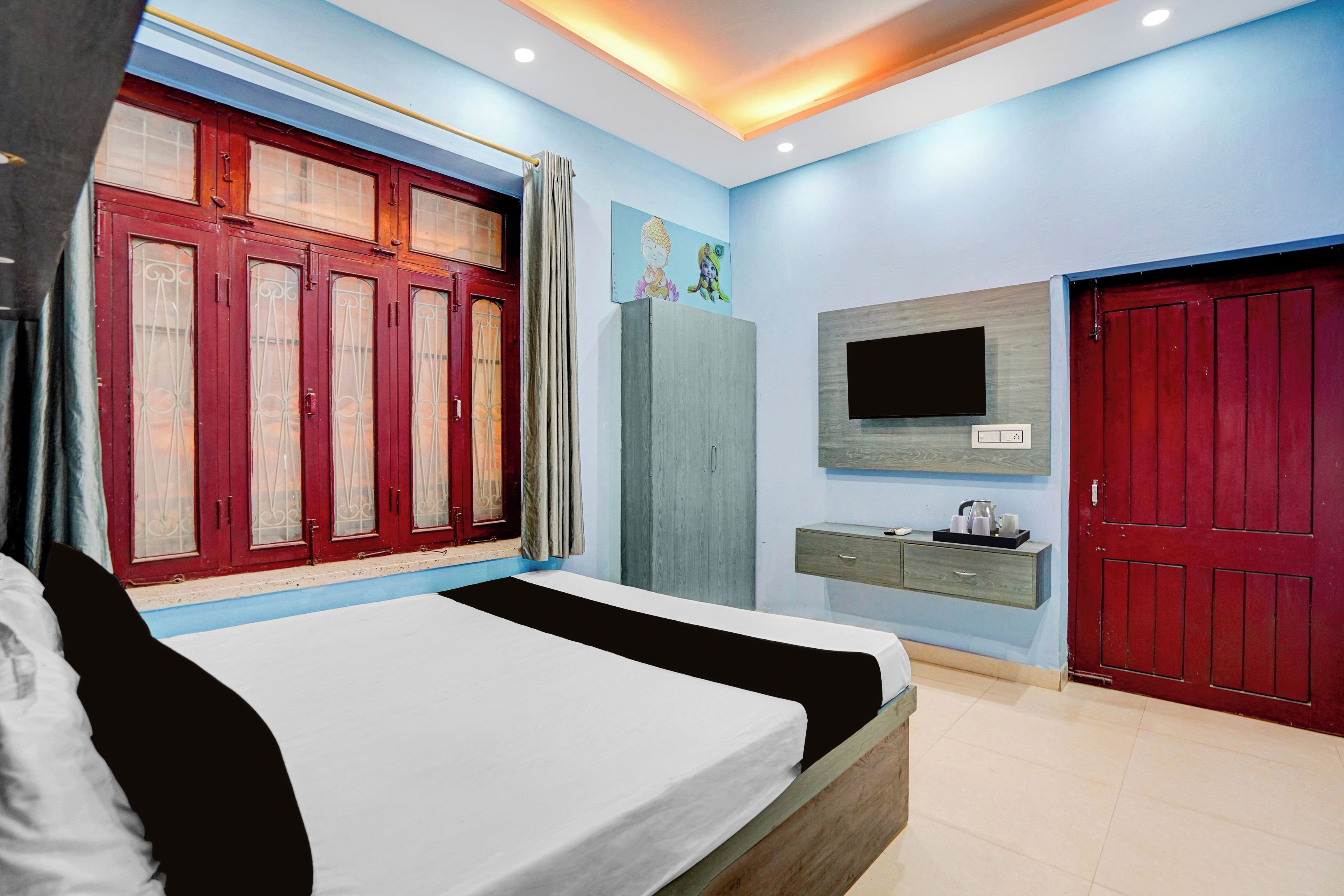 A bedroom with a bed, a TV, a wardrobe, and a window with curtains.