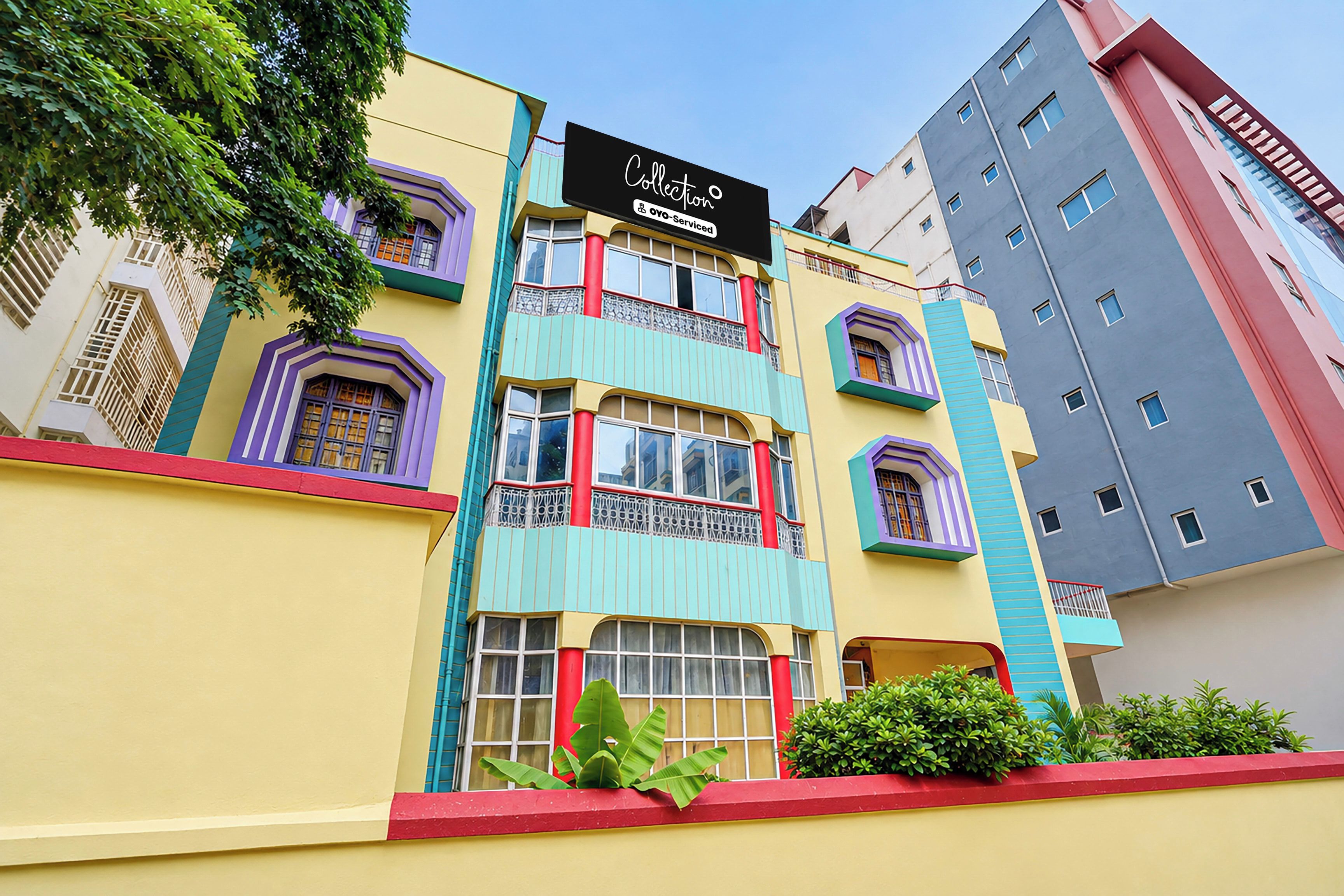 Um edifício de vários andares com fachada colorida, apresentando varandas com grades ornamentadas, janelas amplas e uma placa indicando uma área de serviço.
