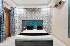 A bedroom with a bed, a headboard, and a patterned wall. - Collection O Patna Airport Road (Danapur)