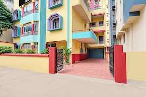 A multi-story residential building with a red and yellow facade, balconies, and a gated entrance. - Collection O Patna Airport Road (Danapur)