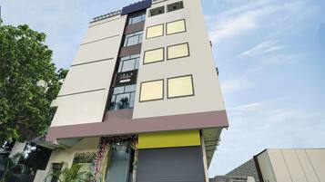 Un edificio de varios pisos con fachada plana, ventanas amplias y un cartel que indica un servicio de empresa.