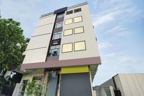 Un edificio de varios pisos con fachada plana, ventanas amplias y un cartel que indica un servicio de empresa.