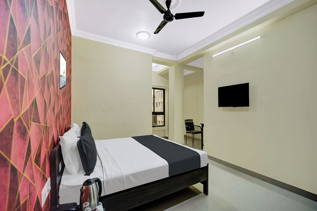 A hotel room with a bed, a ceiling fan, a TV mounted on the wall, and a window.