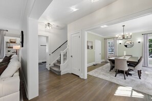 A spacious living area with a staircase, a dining area with a table and chairs, and a view of the outdoors. - Spacious Shaker Heights Retreat  Sleeps 10 (Shaker Heights)
