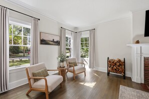 A room with two armchairs, a fireplace, and a window with curtains. - Spacious Shaker Heights Retreat  Sleeps 10 (Shaker Heights)