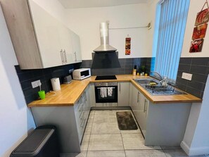 A compact kitchen with a built-in oven, a microwave, and a stainless steel range hood. - Single & Double rooms in Stoke on trent (Stoke-on-Trent)