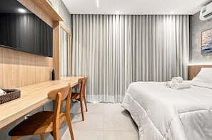 A modern hotel room with a wooden desk, a bed, and a large window with curtains. - Beach Class Rio Vermelho Salvador Near Barra and Ondina by Carpediem (Salvador)