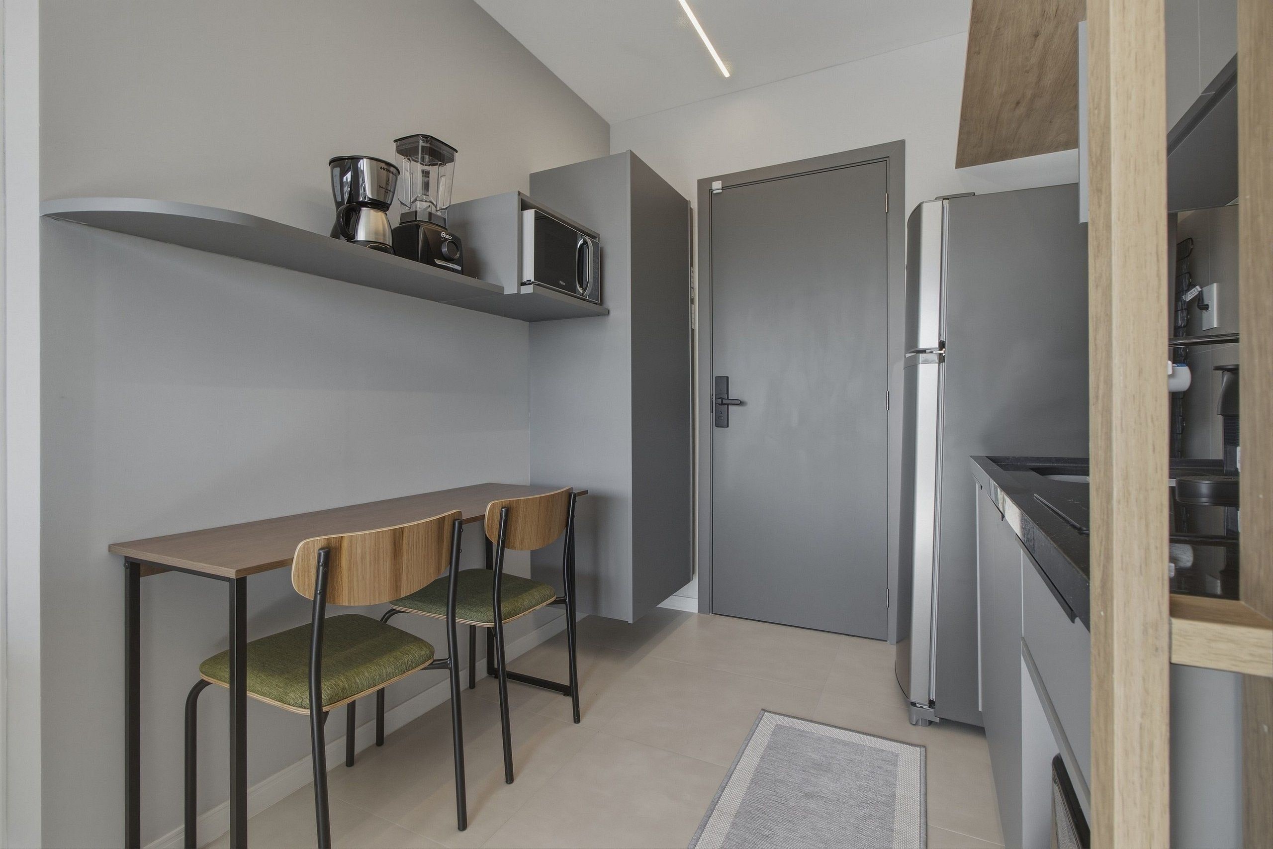 A compact kitchen with a dining table, two chairs, a microwave, and a refrigerator.
