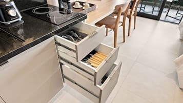 Une cuisine moderne équipée d’une cuisinière intégrée, d’une machine à café et d’un organiseur de tiroir contenant des ustensiles en bois.