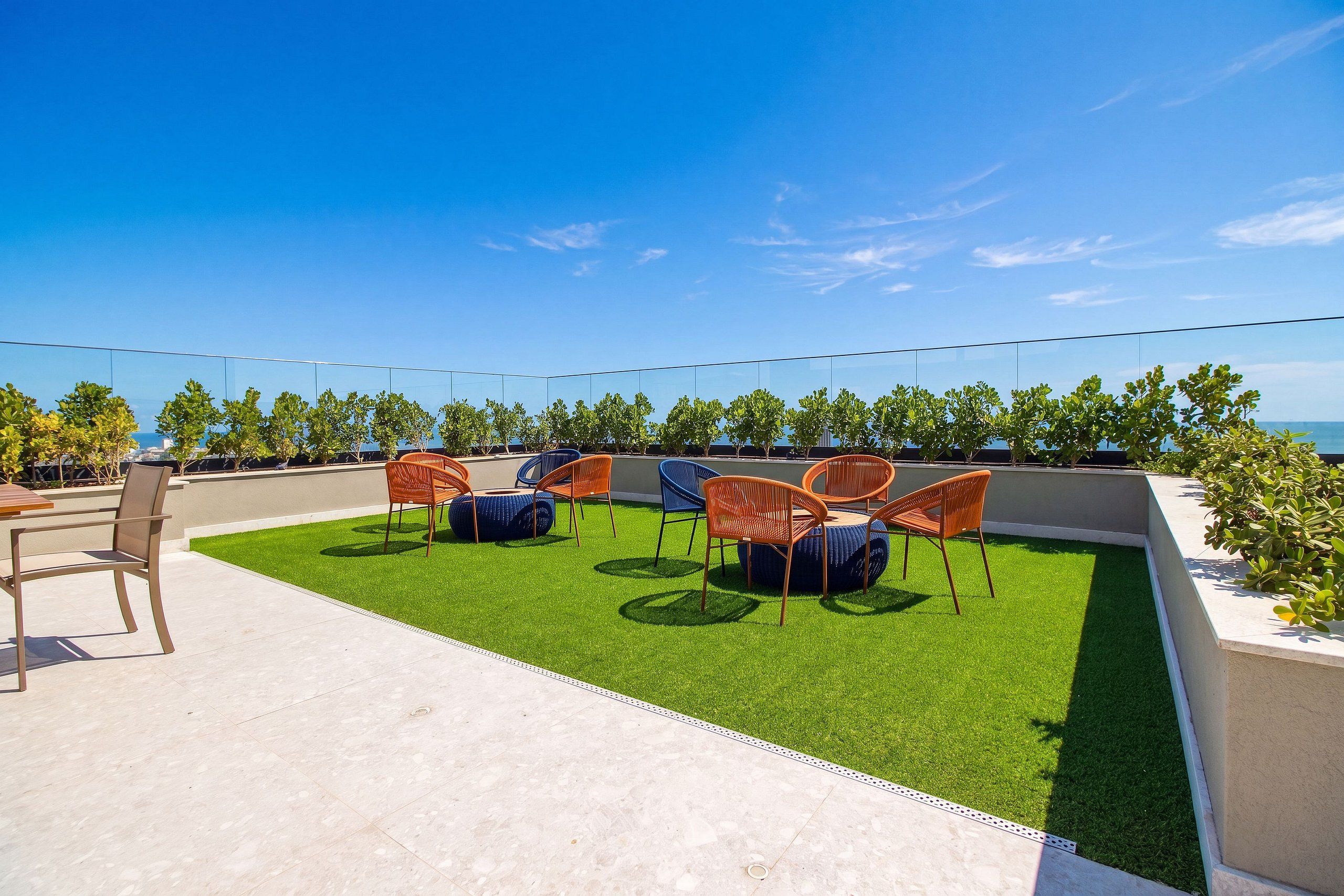 An outdoor seating area with chairs and a table on artificial grass, overlooking a body of water.