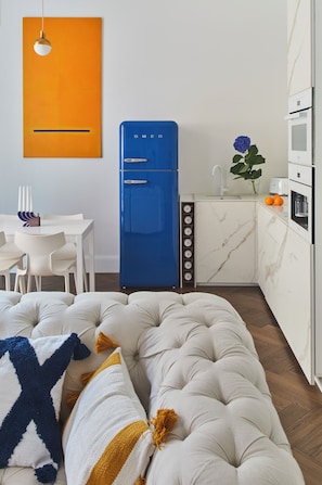 A modern kitchen with a blue refrigerator, white cabinetry, and a marble backsplash. - CocoVita - The Ivy Residence - Old Town (Wrocław)