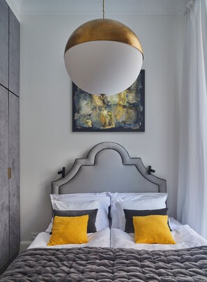 A bedroom with a bed, a hanging light fixture, and a painting on the wall. - CocoVita - The Ivy Residence - Old Town (Wrocław)
