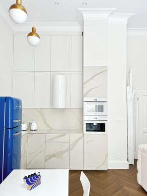 Eine moderne Küche mit weißen Schränken, einem blauen Kühlschrank und einem weißen Backofen.