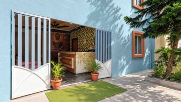 A building entrance with a blue exterior, a Buddha statue, and two potted plants.