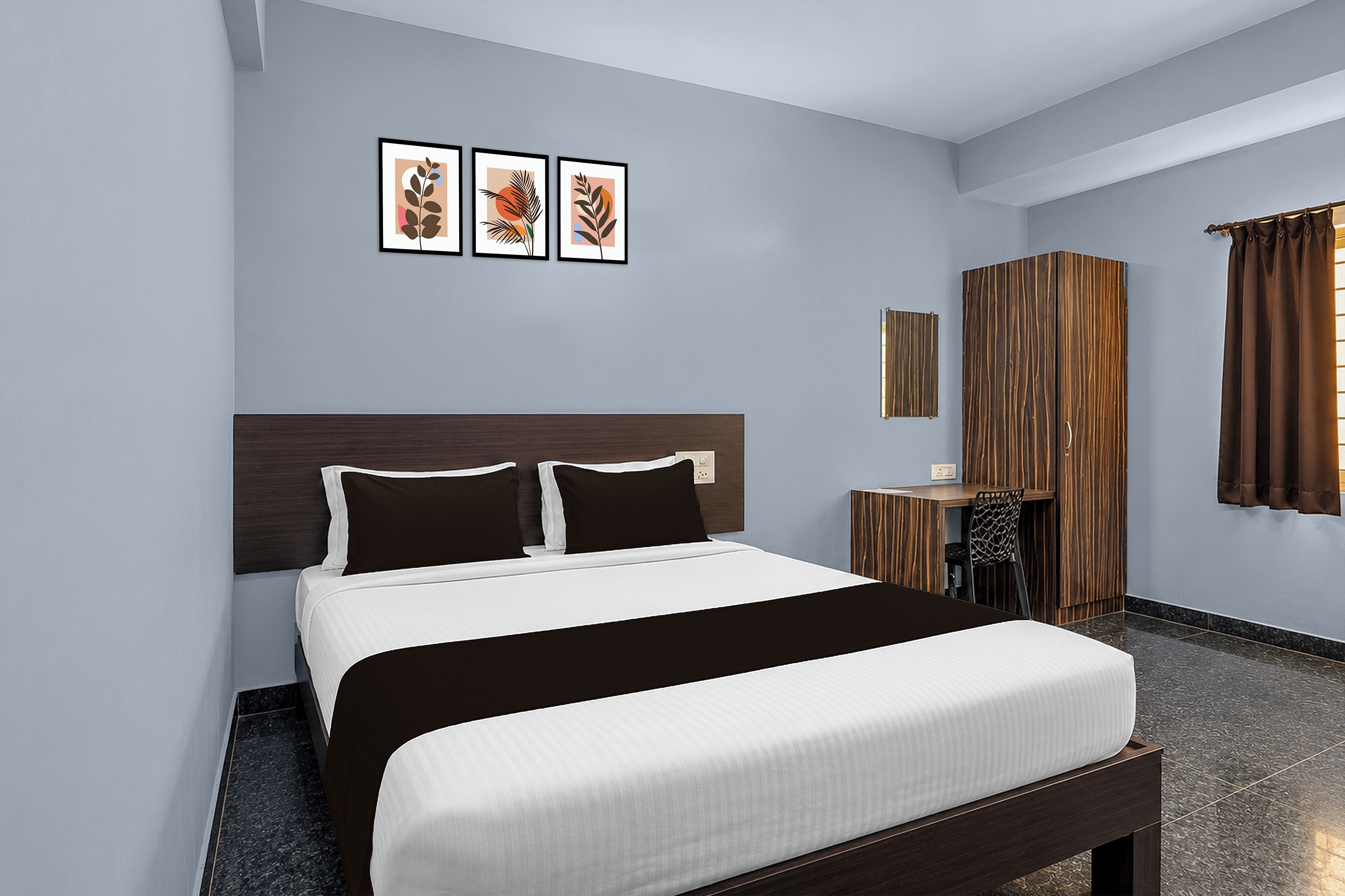 A hotel room with a large bed, a wooden headboard, a small desk, a mirror, and a window with curtains.