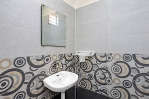 Een badkamer met een wit wastafelmeubel, een spiegel en wandtegels met een patroon.