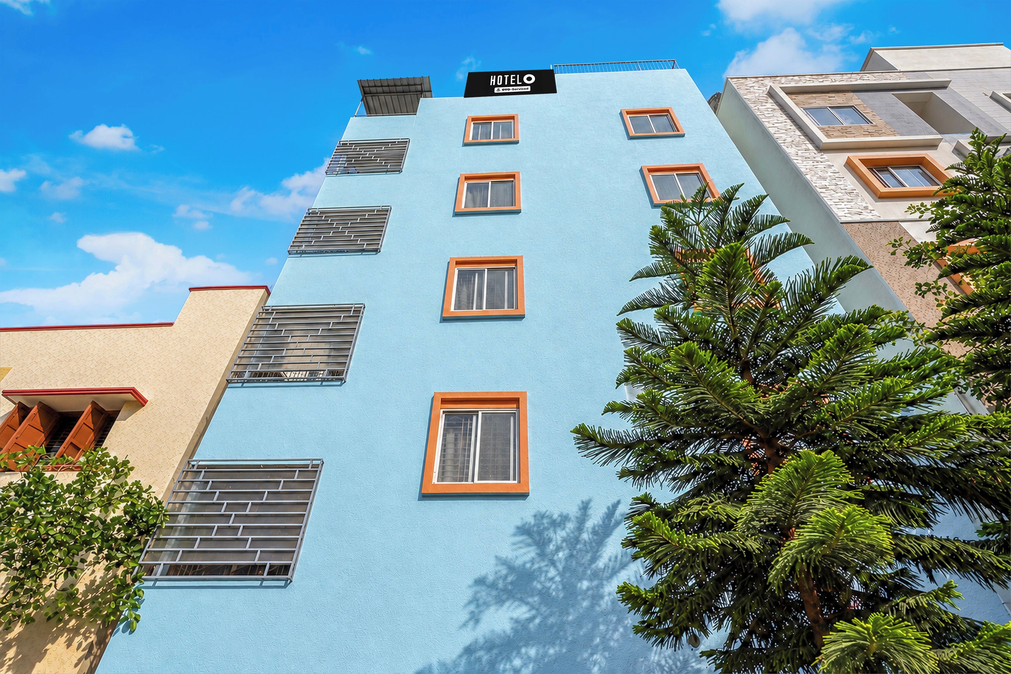 Un edificio de hotel de varios pisos con fachada azul, múltiples ventanas con marcos naranjas y un letrero que indica que es un hotel.