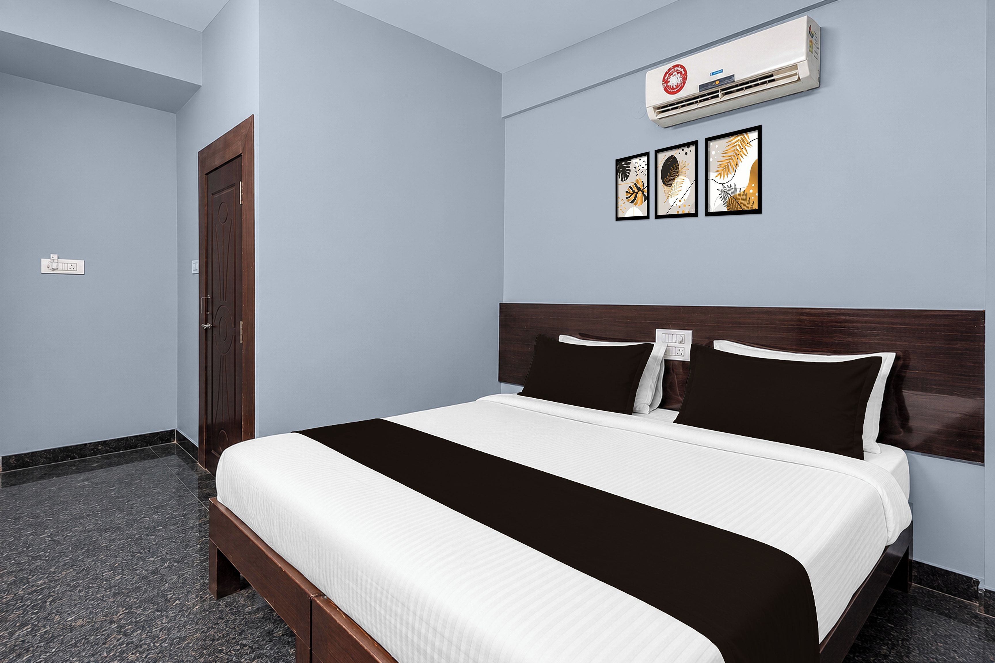 Habitación de hotel con una cama, aire acondicionado de pared, una puerta y un enchufe.