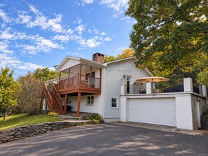 A two-story house with a covered porch, a garage, and a stone retaining wall. - Mountain views, Family friendly, 4 Bed and 3 Bath Home Near Windham Mountain (Acra)