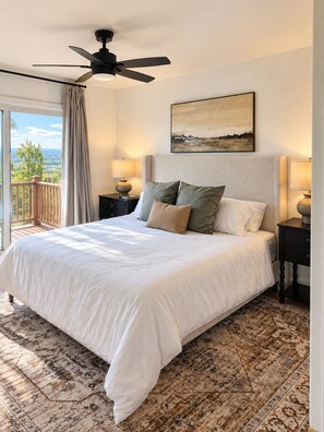 A bedroom with a large bed, a ceiling fan, a view of the outdoors, and a painting on the wall. - Mountain views, Family friendly, 4 Bed and 3 Bath Home Near Windham Mountain (Acra)