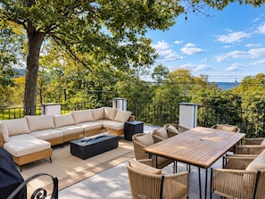 An outdoor patio with a sofa, table, and chairs, surrounded by trees and a view of the landscape. - Mountain views, Family friendly, 4 Bed and 3 Bath Home Near Windham Mountain (Acra)