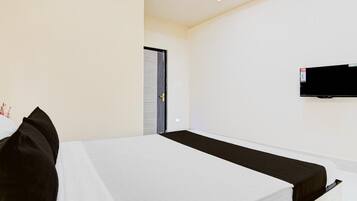 A hotel room with a bed, a television mounted on the wall, and a door leading to another room.