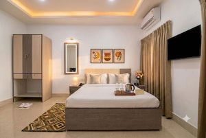 A hotel room with a large bed, a wardrobe, a flat-screen TV, and a bedside table with a tray of breakfast items.