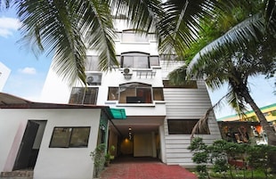 A two-story building with a central entrance, surrounded by palm trees.