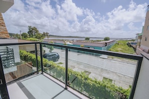Ein Balkon mit Blick auf eine Straße, ein parkendes Auto und ein Gebäude gegenüber.
