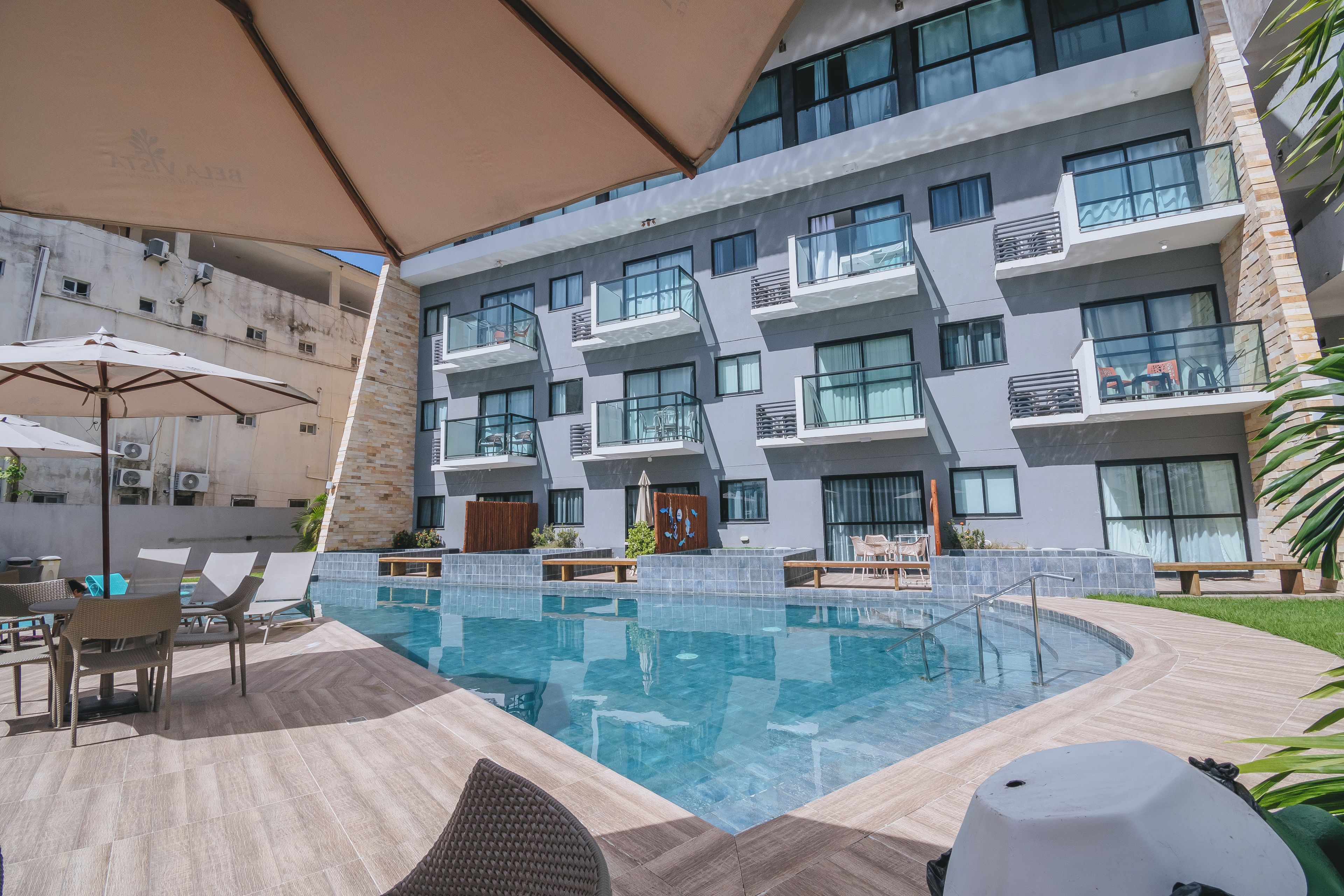 A modern hotel with a swimming pool, outdoor seating, and a view of the building's exterior.