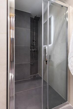 A modern shower with a glass door, a handheld showerhead, and a wall-mounted control panel. - Elegant Urban Flat Near Center (Kallithea)