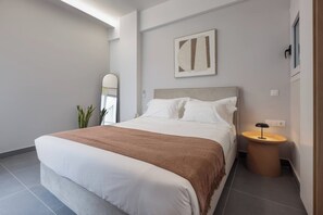 A modern bedroom with a large bed, a bedside table, a mirror, and a wall-mounted artwork. - Elegant Urban Flat Near Center (Kallithea)