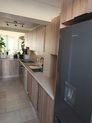 A modern kitchen with wooden cabinets, a stainless steel refrigerator, and a built-in oven. - 2 Bed House Dream Sea Views (CN)
