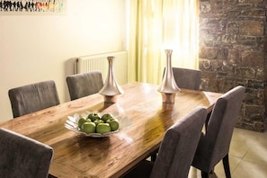 A dining table with six chairs, two vases, and a bowl of green apples. - Peaceful Pool Villa in Crete Countryside (Crete)