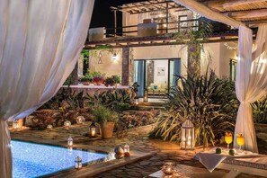 A pool area with stone flooring, surrounded by potted plants and candles. - Peaceful Pool Villa in Crete Countryside (Crete)