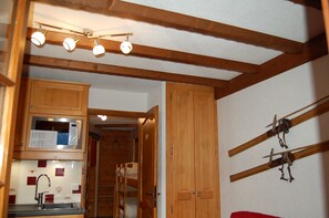 A kitchen with wooden beams, a microwave, and a hanging rack. - Vrbo Property (Châtel)