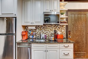 A modern kitchen with stainless steel appliances, white cabinetry, and a tiled backsplash. - The Lover's Carriage | Jacuzzi for Two (Savannah)